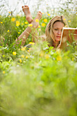 Young woman lying on meadow and reading book