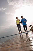 Zwei Personen joggen auf Holzsteg