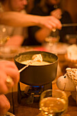 People dining a cheese fondue in restaurant, Saas-Fee, Valais, Switzerland