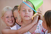 Girls  (5-8 years), one girl with bucket on head, eyes closed