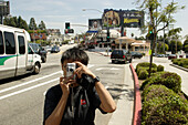 Japanischer Tourist fotografiert den Sunset Boulevard, Werbetafeln, Werbeplakate, Plakate, Werbung,Los Angeles, Kalifornien, Vereinigte Staaten von Amerika, U.S.A.