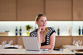 Woman sitting in restaurant, laptop on table