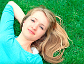 junge Frau liegt im Gras, Deutsche, blond, kaukasisch, entspannen, chillen, Freizeit, Blick in die Kamera, offenes Haar, türkises Shirt, Wiese