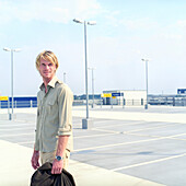 Mann auf Parkplatz, Deutscher, blond, Deutschland, hält Jacke in Hand, unrasiert, leerer Parkplatz, lächelt, freundlich