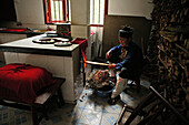 A nun heating up the stove in the kitchen of Nunnery Huanting, Heng Shan South, Hunan province, China, Asia