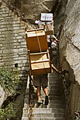 porters carry furniture, building material on their backs up steep mountain steps to the summit, Taoist mountain, Hua Shan, Shaanxi province, Taoist mountain, China, Asia