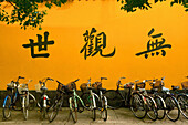 Yellow monastery wall with bicycles and calligraphy, Buddhist Island of Putuo Shan near Shanghai, East China Sea, China