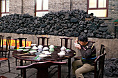Man eating lunch in the monastery canteen, coal used for cooking in the background, during the birthday celebrations for Wenshu, Mount Wutai, Wutai Shan, Five Terrace Mountain, Buddhist Centre, town of Taihuai, Shanxi province, China
