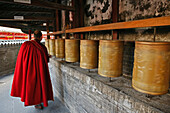 Lama monk turns the prayer wheels at the base of the Great White Pagoda, during the birthday celebrations for Wenshu, Tayuan Monastery, Wutai Shan, Five Terrace Mountain, Buddhist Centre, town of Taihuai, Shanxi province, China