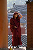 portrait, young buddhist monk in red robe, framed by monastery walls, Xiantong Monastery, Wutai Shan, Five Terrace Mountain, Buddhist Centre, town of Taihuai, Shanxi province, China, Asia
