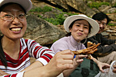 smiling Chinese Tourists with local speciality, fried chicken feet, typical Chinese snack, China, Asia