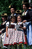 Gruppe von Frauen in Tracht mit zwei singenden Mädchen im Dirndl, Trachtenwallfahrt nach Raiten, Chiemgau, Oberbayern, Bayern, Deutschland