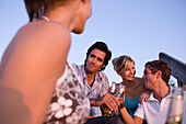 Group of young people sitting on jetty, drinking beer