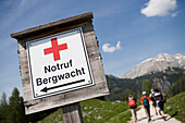 A group of hikers and Mountain Rescue Emergency Phone Sign, Near Jenner Mountain und Lake Koenigssee, near Berchtesgaden, Berchtesgadener Land, Bavaria, Germany