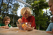 Boy with wet hair bending over a dish with water and an apple and smiling at camera, children's birthday party