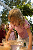 Nasses Mädchen beugt sich über eine Schüssel mit Wasser und einem Apfel, Kindergeburtstag