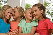 Four girls standing side by side and whispering, children's birthday party