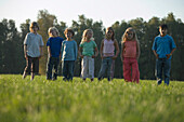 Children standing side by side on grass, children's birthday party