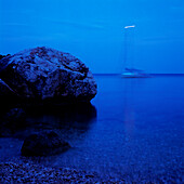 Fels liegt am Ufer der Adria, Segelboot im Hintergrund, Dalmatien, Kroatien