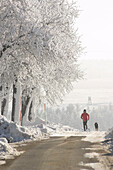 Male jogger with dog in winter, Upper Austria