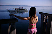 Girl about to jump into the lake from a wooden diving platform, steamboat in the background, Utting, Ammersee,  Bavaria, Germany