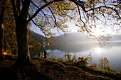 A couple walking along the shore of lake Kochelsee in Autumn, Bavaria, Germany