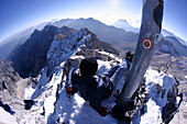 Man relaxing at the foot of the summit cross, Zugspitze, Bavaria, Germany
