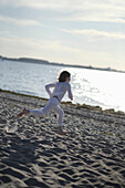 Girl running over sandy beach at Baltic Sea, Travemuende Bay, Schleswig-Holstein, Germany