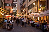 People strolling over Hirschpaltz, passing different pavement cafes and restaurants in the evening (right hand: Restaurant Swiss Chuchi of the Hotel Adler), Niederdorfstrasse, Zurich, Canton Zurich, Switzerland