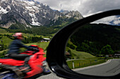 A motorcyclist and view of Dientner Sattel and Hochkonig pass with reflection in car wing mirror, Salzburg, Austria