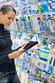 Junge Frau steht im Geschäft und liest in einer Zeitschrift