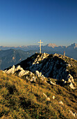 hiker at cross on summit of Zwiesel with view to Berchtesgaden range, Chiemgau, Upper Bavaria, Bavaria, Germany