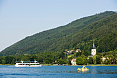 View over Lake Ossiach with excursion boat to the chuch Maria Himmelfahrt of the former Benedictine monastery (oldest Benedictine monastery of Carinthia) Ossiach, Carinthia, Austria