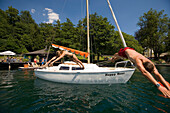 Couple diving from a sailing boat into Millstaetter See, the deepest lake in Carinthia, Millstatt, Carinthia, Austria