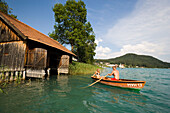 Couple in a rowboat leaving a boathouse, Lake Faak, Carinthia, Austria
