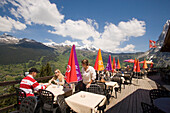 People on sun terrace of the mountain restaurant Pfingstegg, Schreckhorn (4078 m) and Eiger (3970 m) in background, Grindelwald, Bernese Oberland (highlands), Canton of Bern, Switzerland