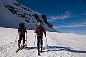 Two people glacier hiking at Jungfraufirn glacier to Mönchsjoch Hut (3650 m highest restaurant in the Swiss Alps), Grindelwald, Bernese Oberland (highlands), Canton of Bern, Switzerland