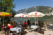 Guests sitting on terrace of a cafe at lake Hallstatt, Hallstatt, Salzkammergut, Upper Austria, Austria