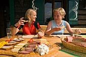 Zwei Frauen essen eine Brotzeit, Jause, Amoseralm 1198 m, Dorfgastein, Gasteiner Tal, Salzburg, Österreich