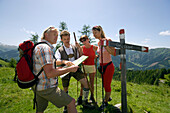 Shepherd explaining the way to Bichlalm, 1731 m, on a map to three hikers, Grossarl Valley, Salzburg, Austria