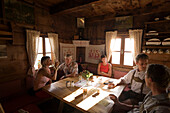 Group of people sitting in the Karseggalm Hut (1603 m, one of the oldest mountain hut in the valley), Grossarl Valley, Salzburg, Austria