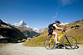 Female mountain biker leaving the mountain village Findeln, Matterhorn, 4478 m, in the background, Zermatt, Valais, Switzerland