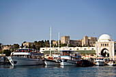 Ships and boats anchoring in Mandraki harbour (translated literally: fold), Palace of the Grand Master and Nea Agora in background, Rhodes Town, Rhodes, Greece