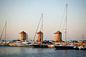 View over Mandraki harbour (translated literally: fold) with anchoring ships to windmills on mole, Rhodes Town, Rhodes, Greece