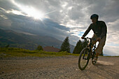 Mountainbiker fährt über Feldweg, Simmental, Wistätthorn (2362 m) im Hintergrund, Lenk, Berner Oberland, Kanton Bern, Schweiz, MR