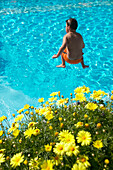 Junge springt ins Wasser, Hotelpool, Familienhotel, gelbe Strauchmargeriten, Österreich