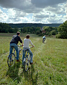 Fahrradausflug, sportliche Familie mit Sohn, mit Fahrrädern auf einer Wiese, im Hintergrund das Schloßhotel Münchhausen, bei Hameln, Weserbergland, Niedersachsen,  Deutschland