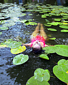 Woman bathing between water lilies, Hotel Neuklostersee, Nakenstorf, Mecklenburg-Western Pomerania, Germany