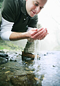Mann trinkt Wasser am Fluß, Wellness, Natur, Gesundheit