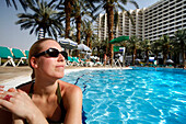 A woman sunbathing in a pool at a hotel resort, Dead Sea, Israel